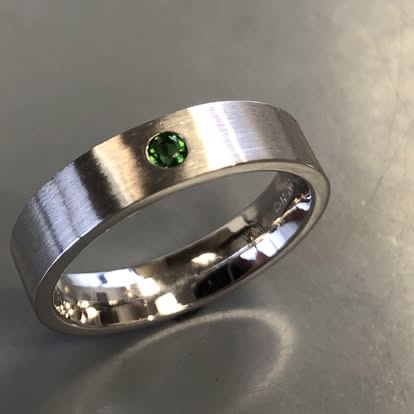 Men's white gold band with a flush-set green gemstone
