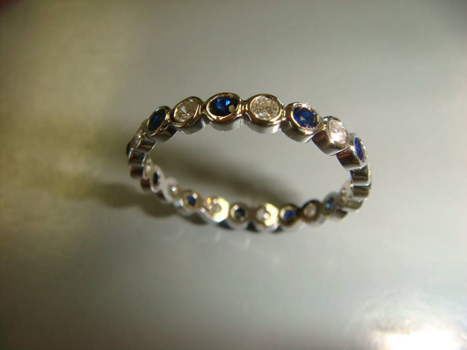 Two-tone eternity band alternating bezel-set blue sapphires and diamonds